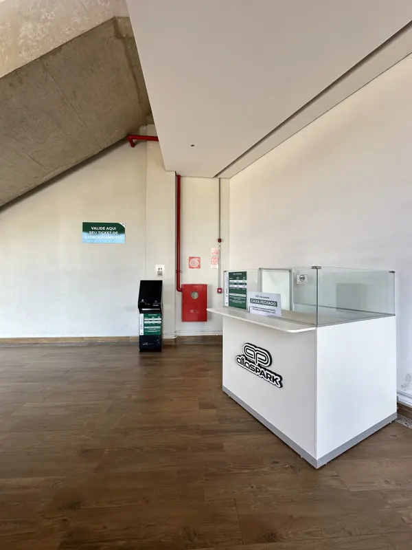 Balcão de atendimento Atlas Park em área interna, com totem ao fundo